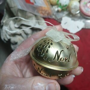 gold metal Christmas bell ornament, featuring the word "Noel" and a ribbon